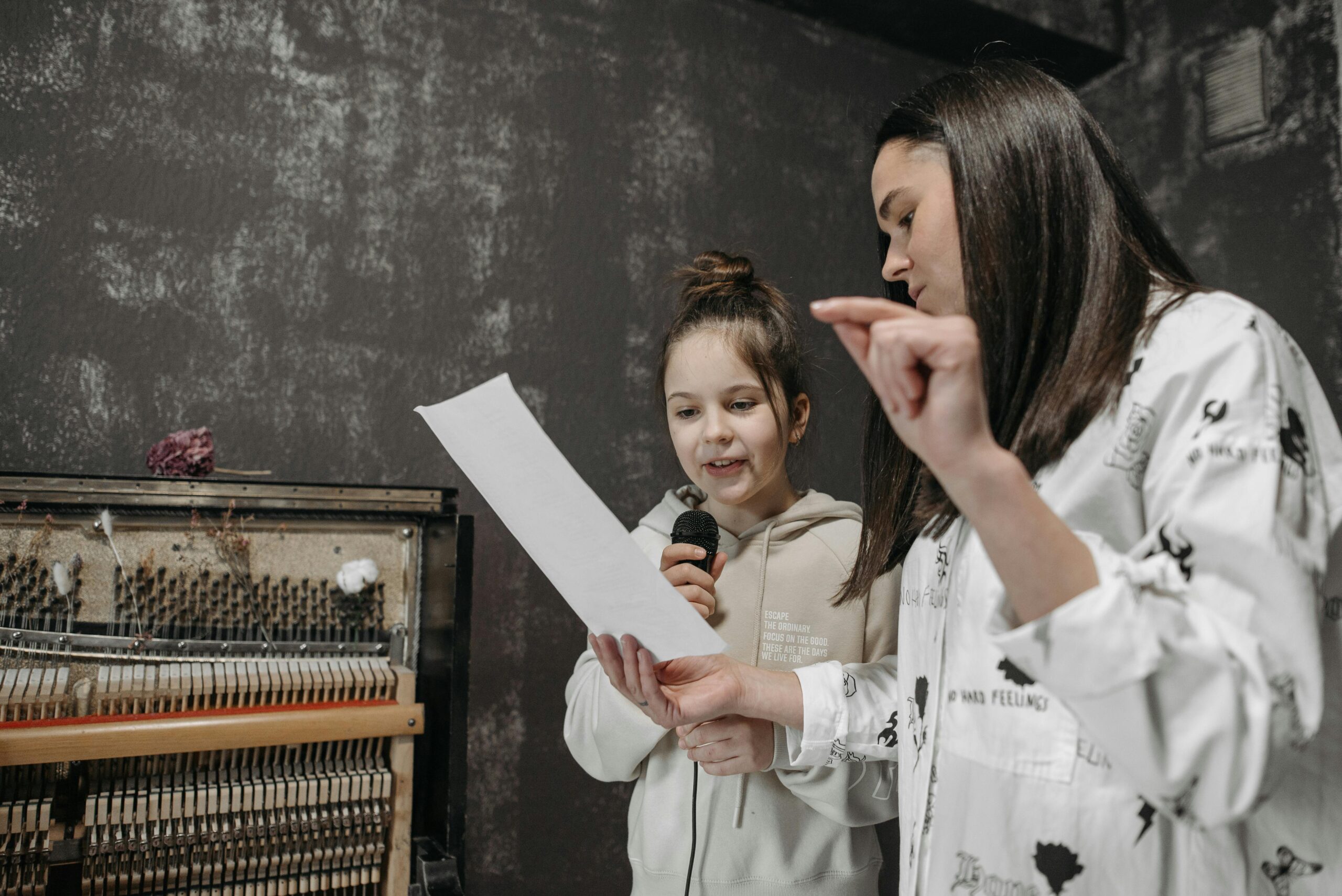 A girl receiving a singing lesson with a microphone in a music studio.